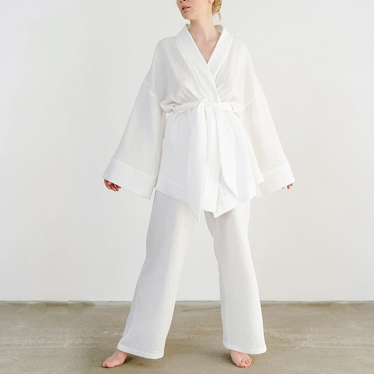 Pyjama kimono blanc porté pieds nus, la ceinture nouée en large nœud à la taille