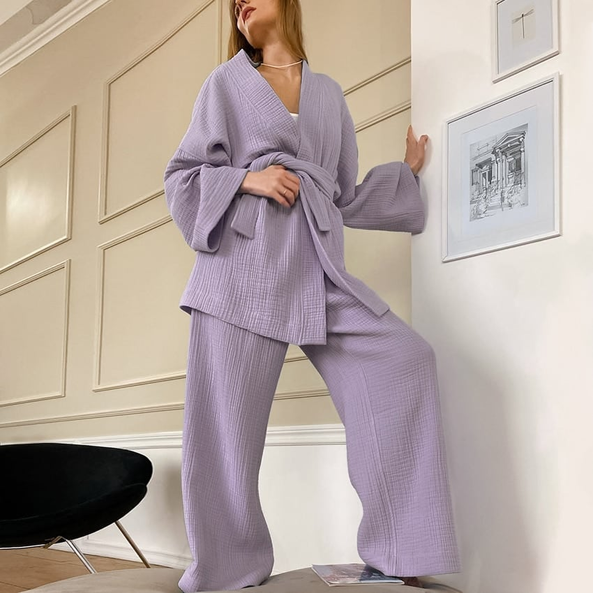 Pyjama kimono violet lilas porté devant un mur à moulures, veste nouée et manches larges