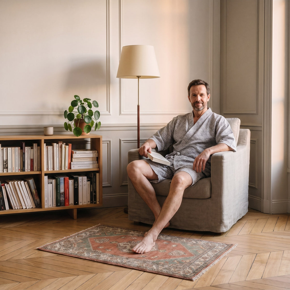Homme en pyjama kimono gris assis dans le fauteuil du coin lecture Image
