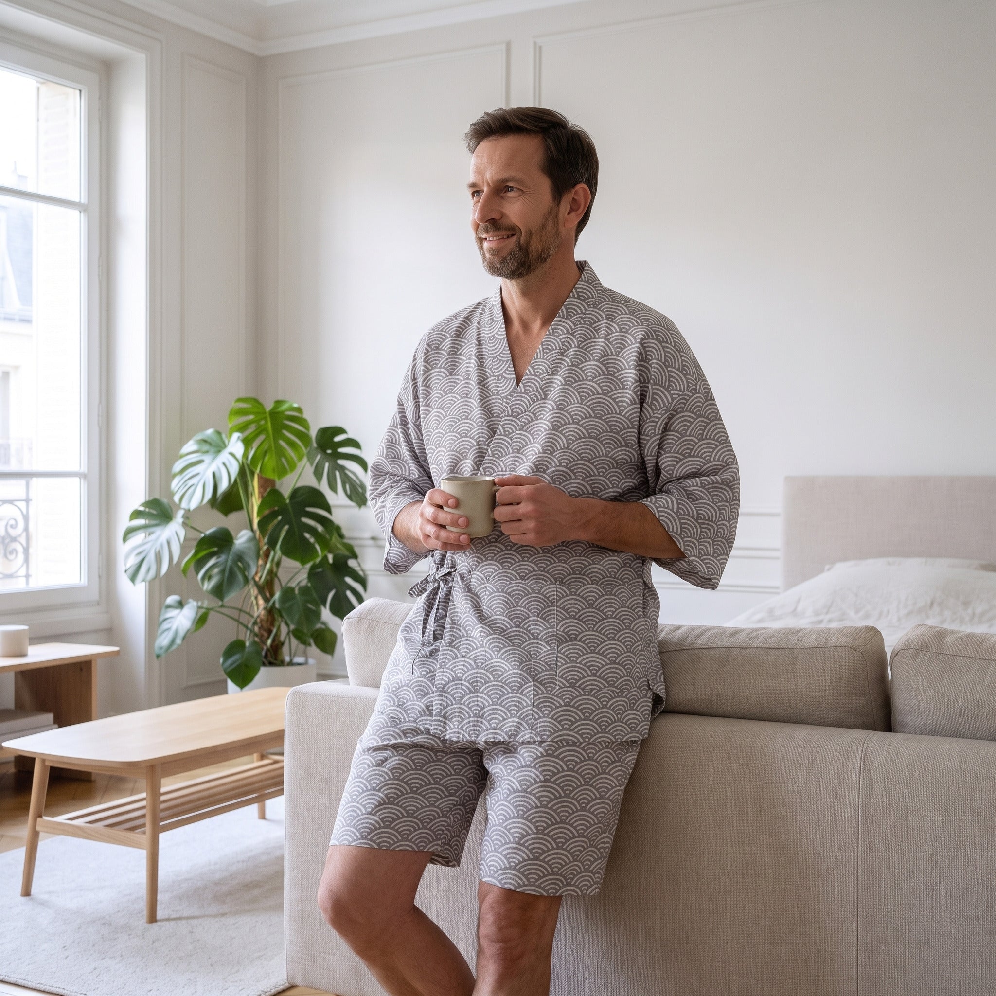 Homme en pyjama kimono gris, une tasse de café à la main, dans le salon Image