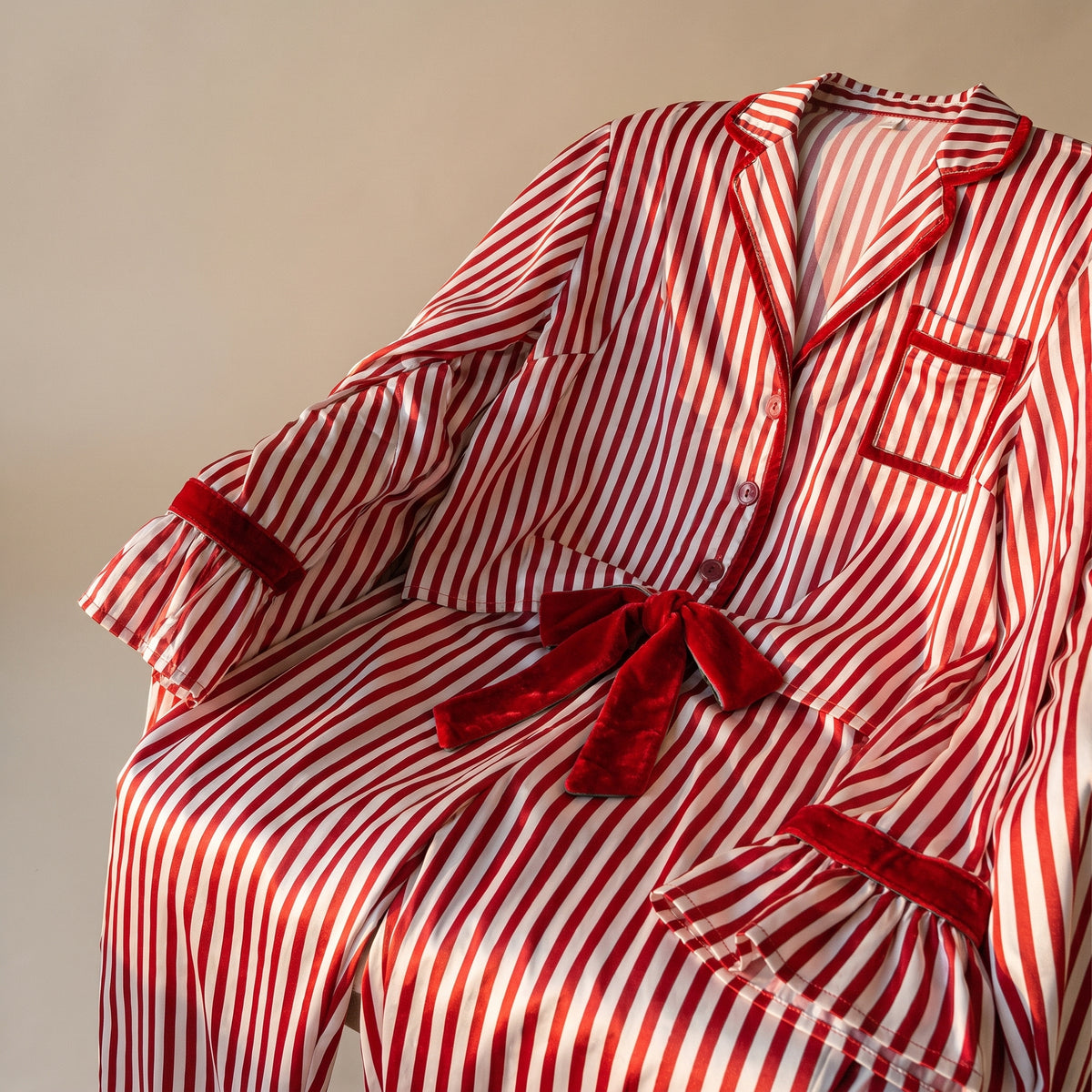 Détail du pyjama de Noël femme rouge rayé, plié sur fond uni