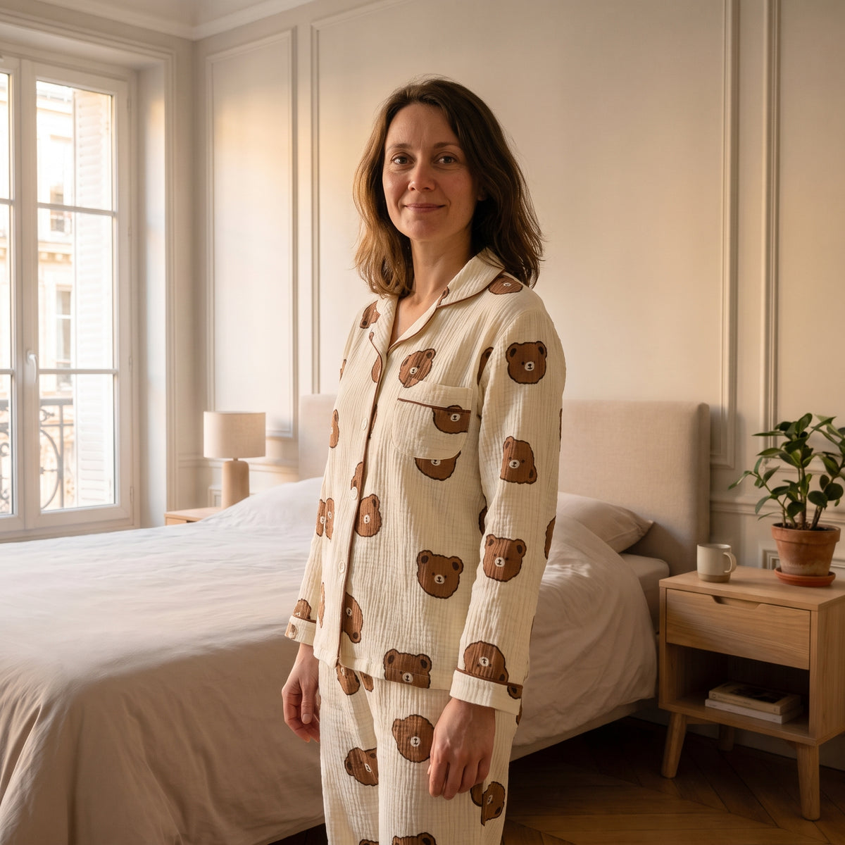 Femme portant le pyjama nounours écru, debout dans une chambre claire, col et poche visibles.