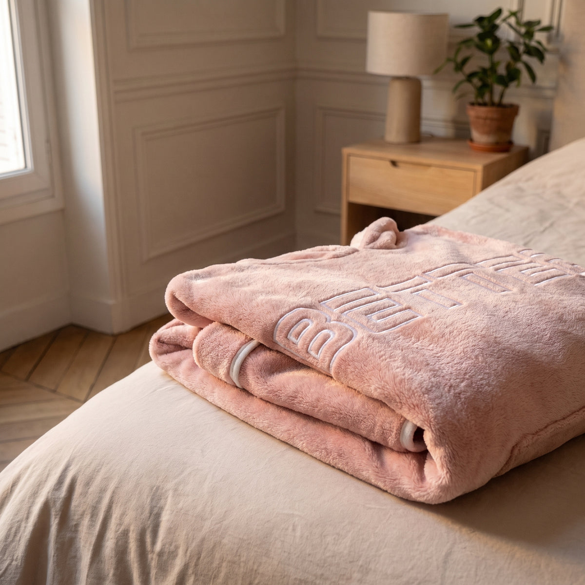 Gros plan sur le pyjama polaire rose replié : le liseré blanc et le mot Better en lettres claires