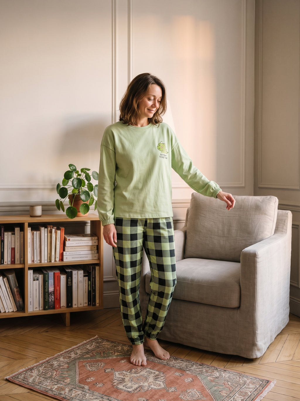 Pyjama femme vert tilleul porté devant une bibliothèque, pantalon à carreaux verts