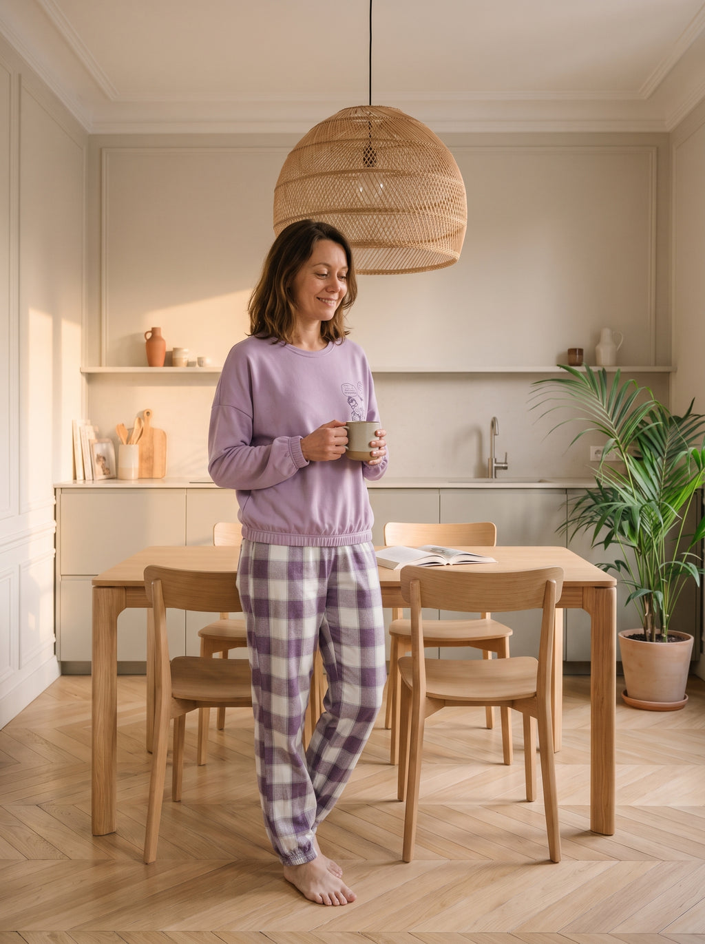Pyjama femme violet lilas porté dans un coin repas, une tasse à la main