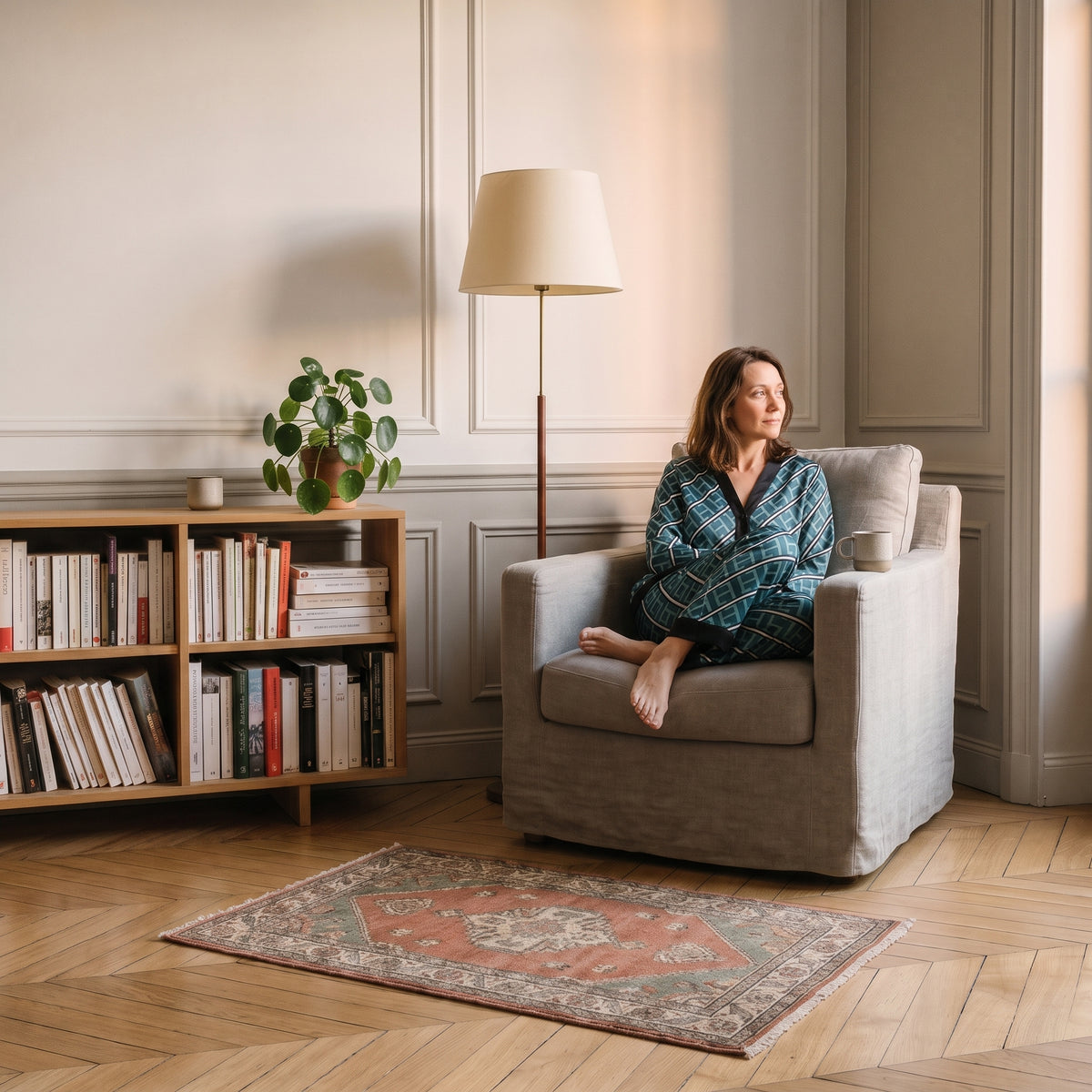 Femme en pyjama de satin assise dans un fauteuil de lecture Image