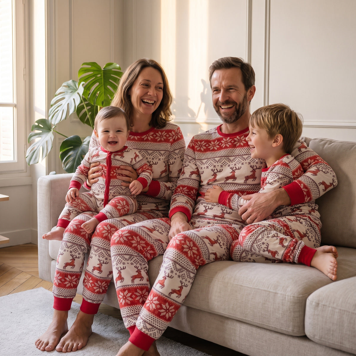 Famille réunie sur le canapé en pyjamas de Noël rayés écru et rouge à motifs rennes assortis