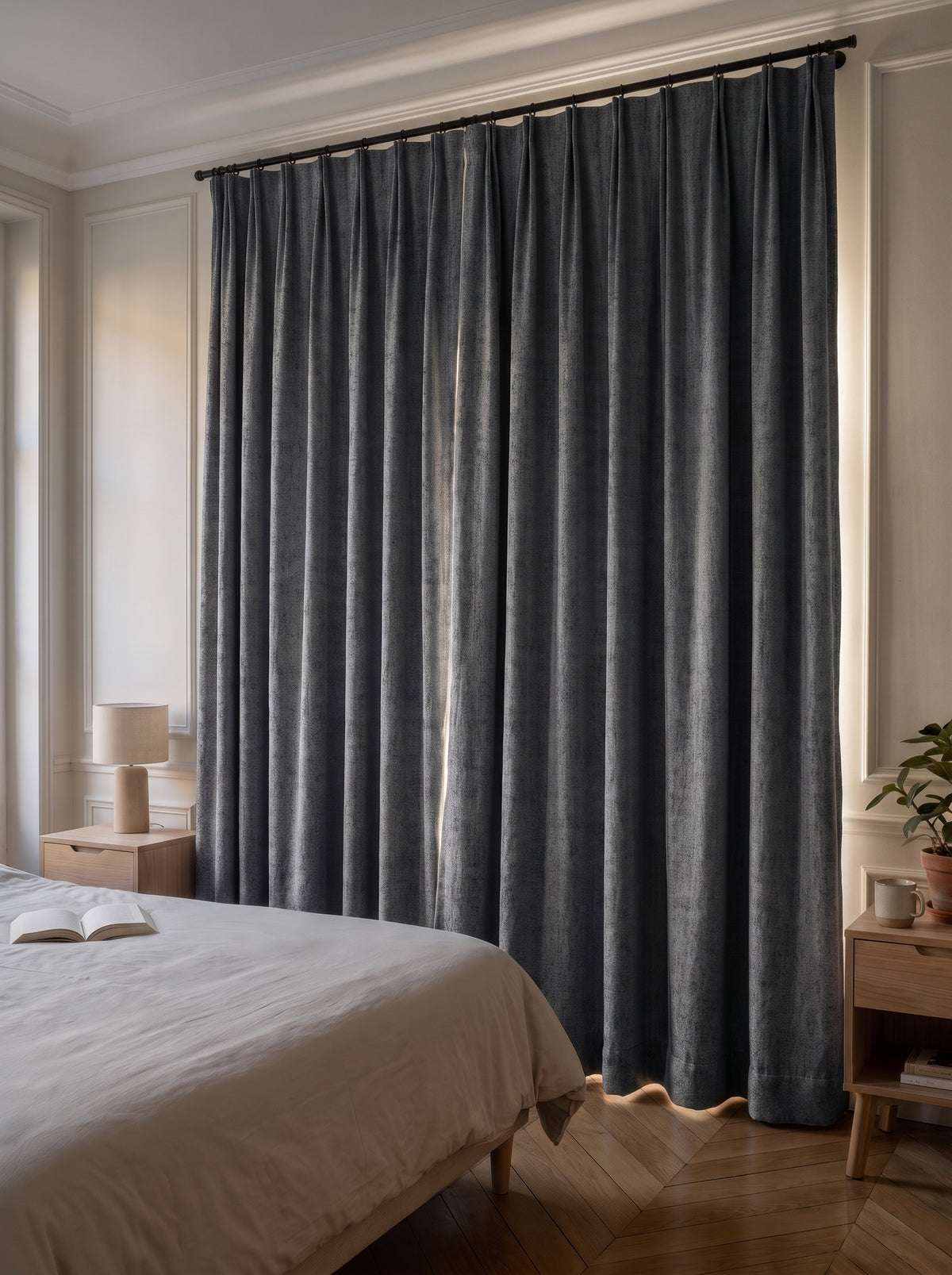 Rideau occultant gris foncé tiré devant la fenêtre d'une chambre, la pièce reste dans la pénombre en pleine journée