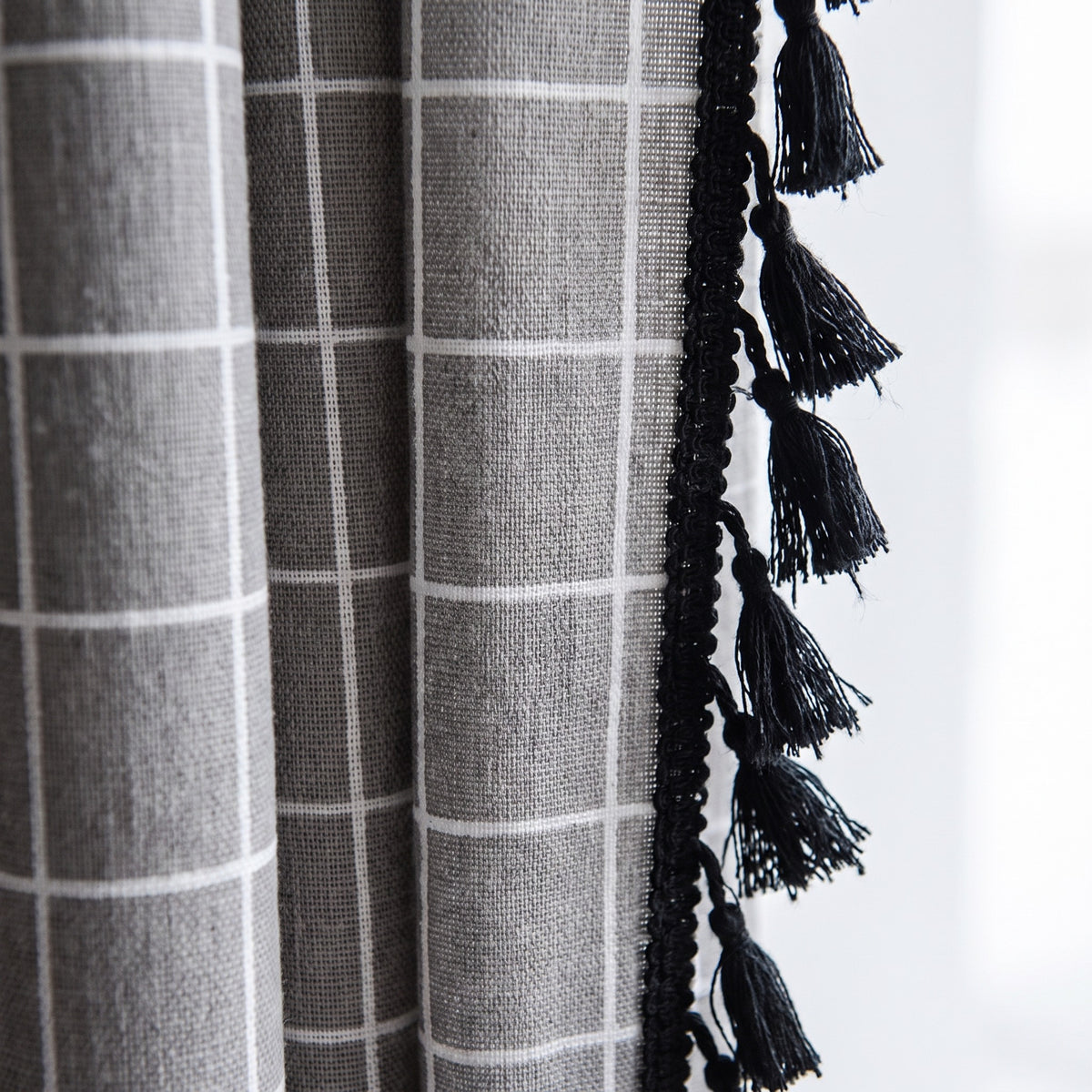 Détail du galon de pompons noirs et du coton à carreaux gris du rideau