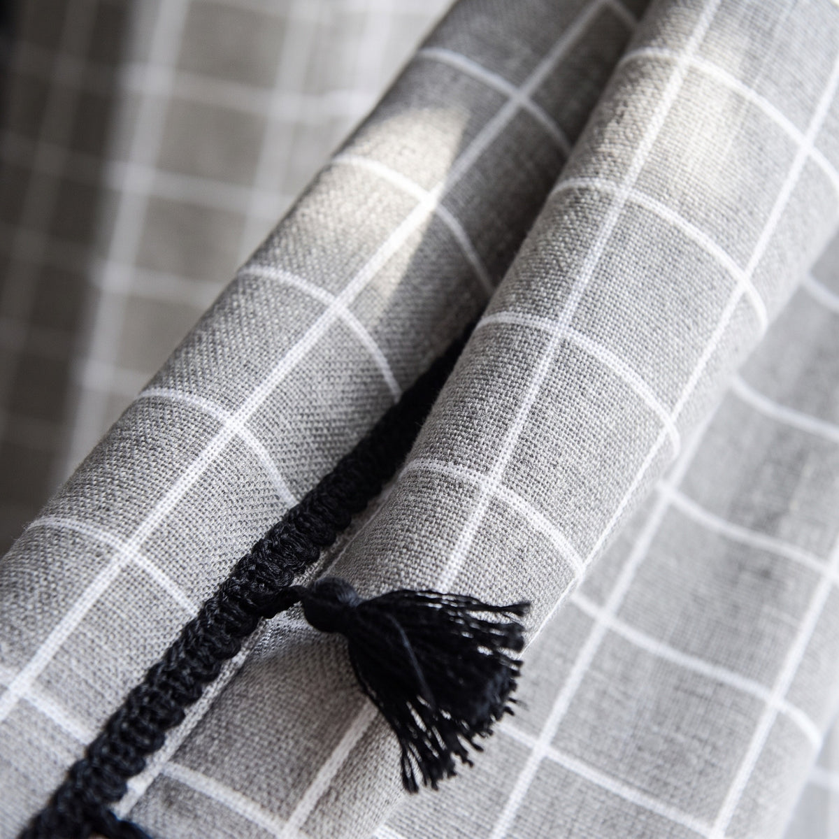 Détail du coton à carreaux gris et d’un pompon noir du rideau Image