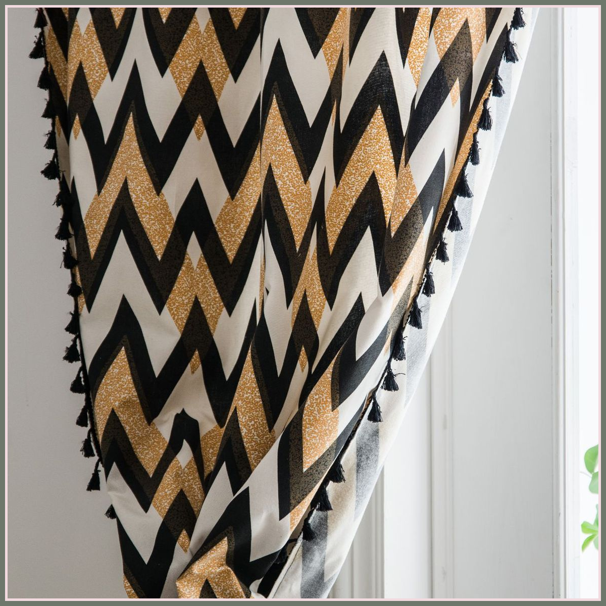 Rideau à chevrons noir et ocre rassemblé près d’une fenêtre Image