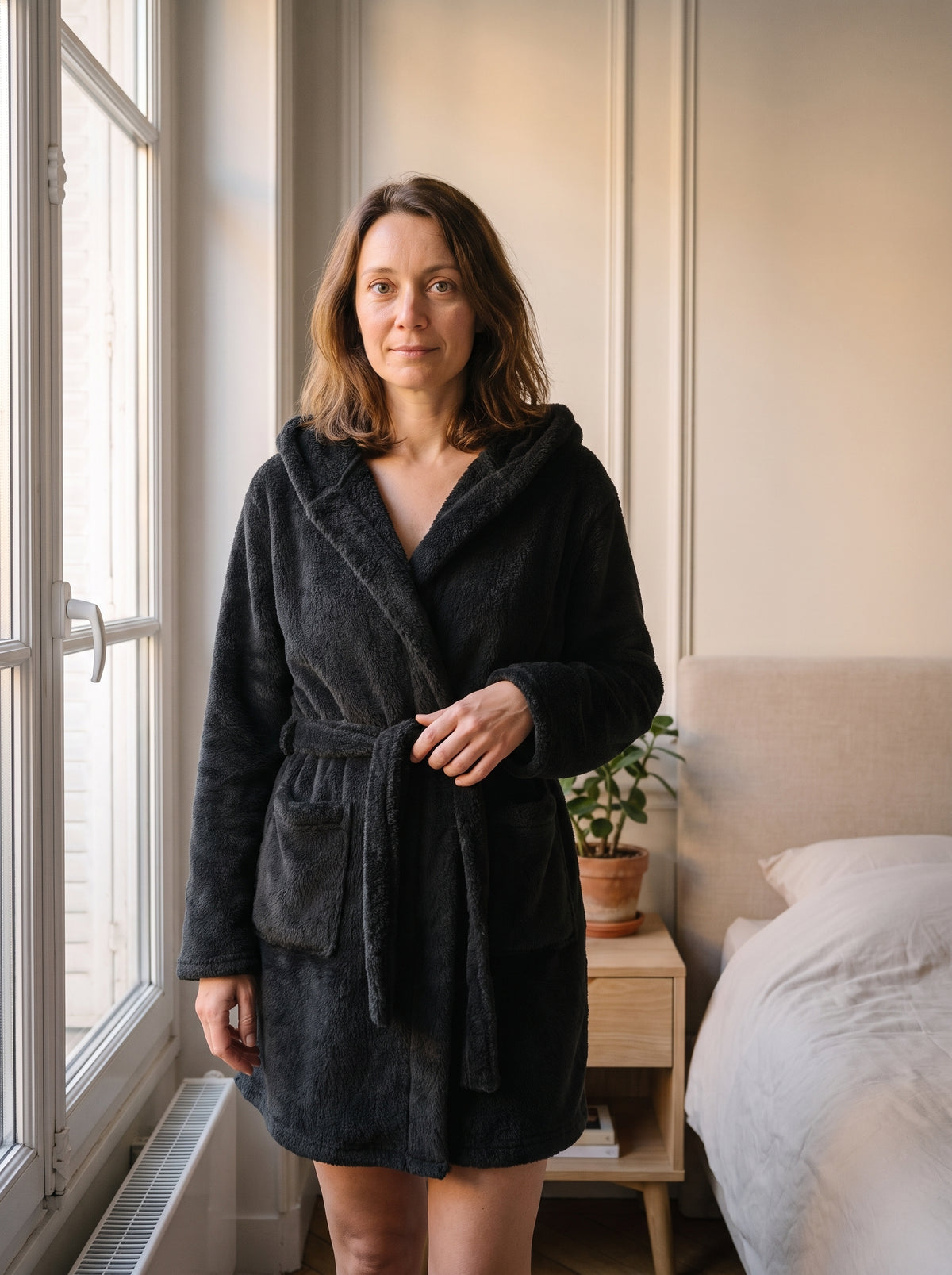 Femme du casting portant la robe de chambre courte noire à capuche dans la chambre