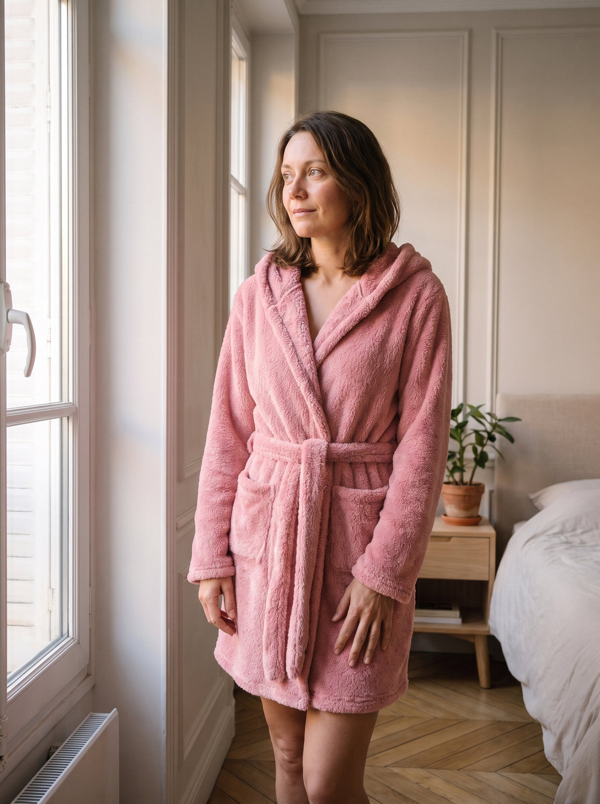 Femme du casting portant la robe de chambre courte rose à capuche dans le coin lecture