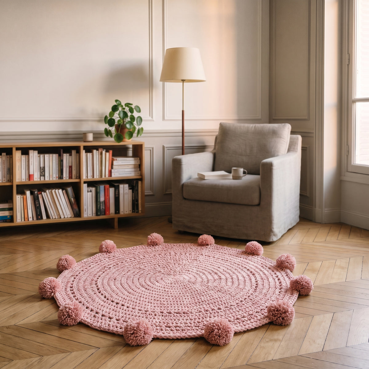 Tapis rond rose à pompons posé dans un coin lecture