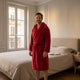 Homme du casting portant la robe de chambre Rouge à capuche dans la chambre