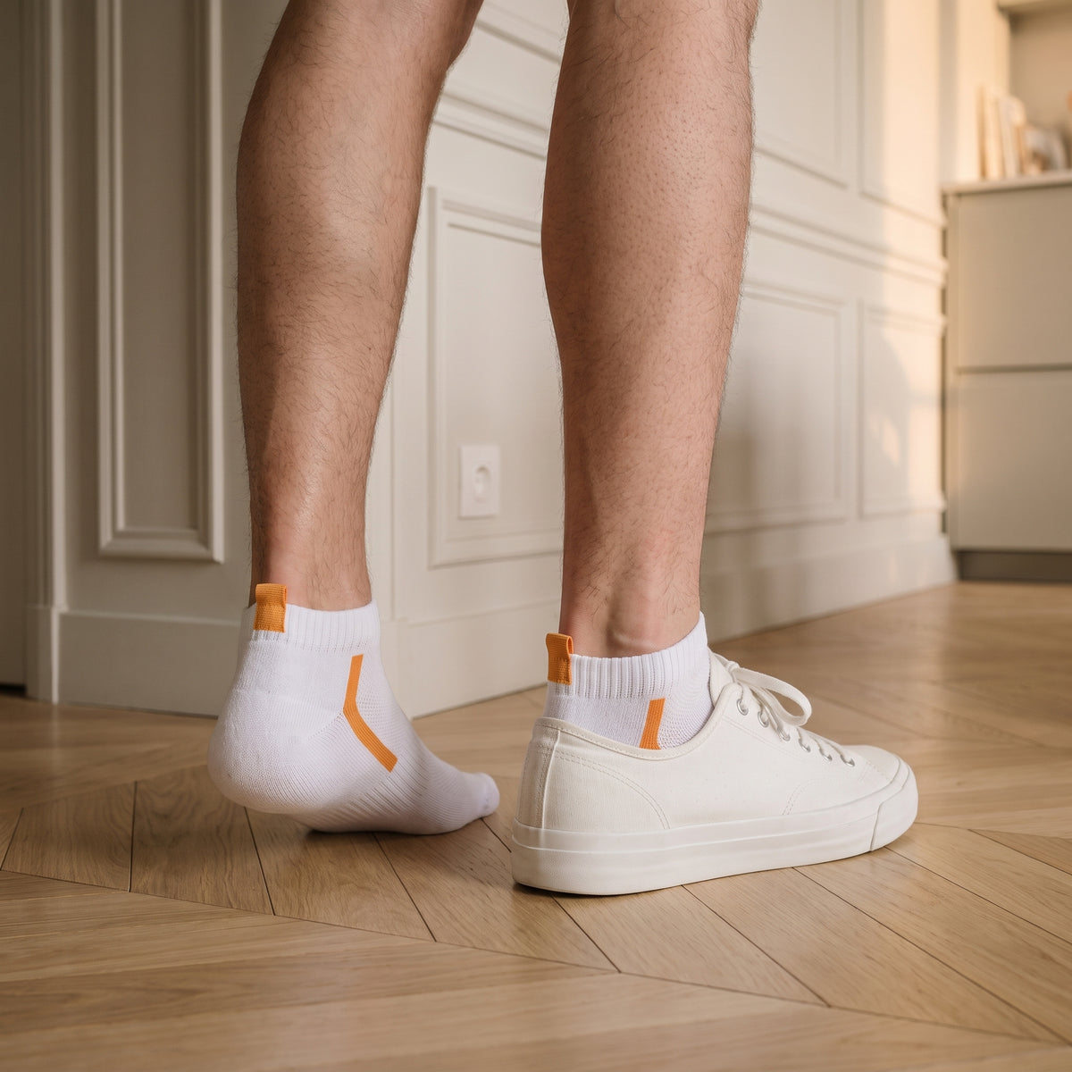 Un pied chaussé d'une basket basse, l'autre en socquette blanche à chevron jaune, sur un parquet