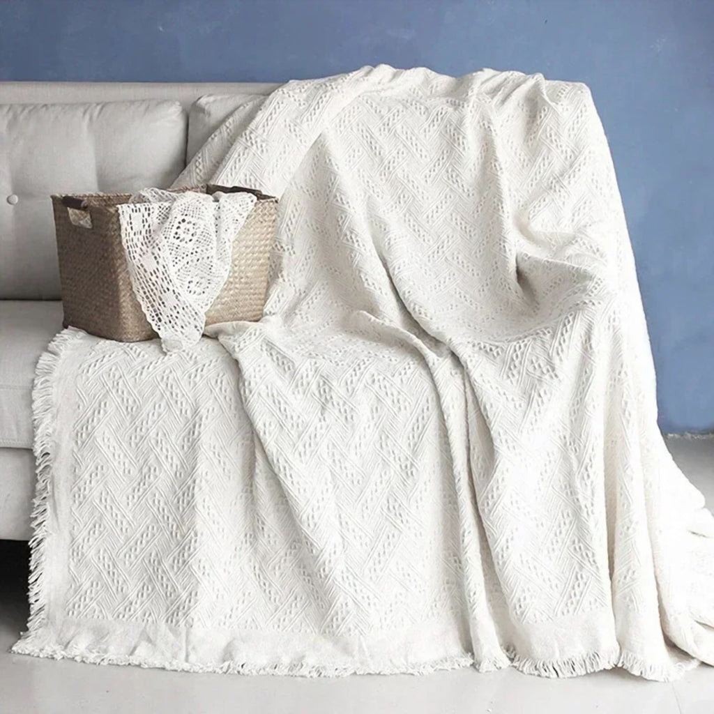 Maille en relief et franges du plaid tricoté blanc cassé, vues de près