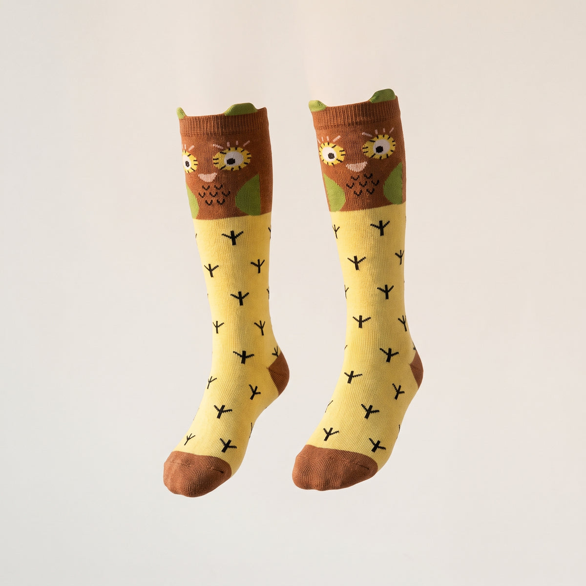 Paire de chaussettes chouettes jaunes présentée sur fond uni
