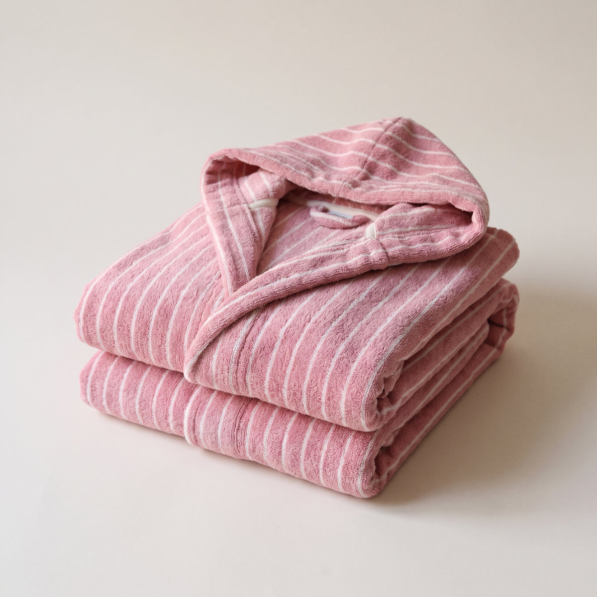 Peignoir femme rose rayé à capuche sur fond uni