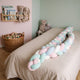 Tour de lit tressé rose déroulé sur le lit d'enfant, brins roses, bleus, vert d'eau et blancs