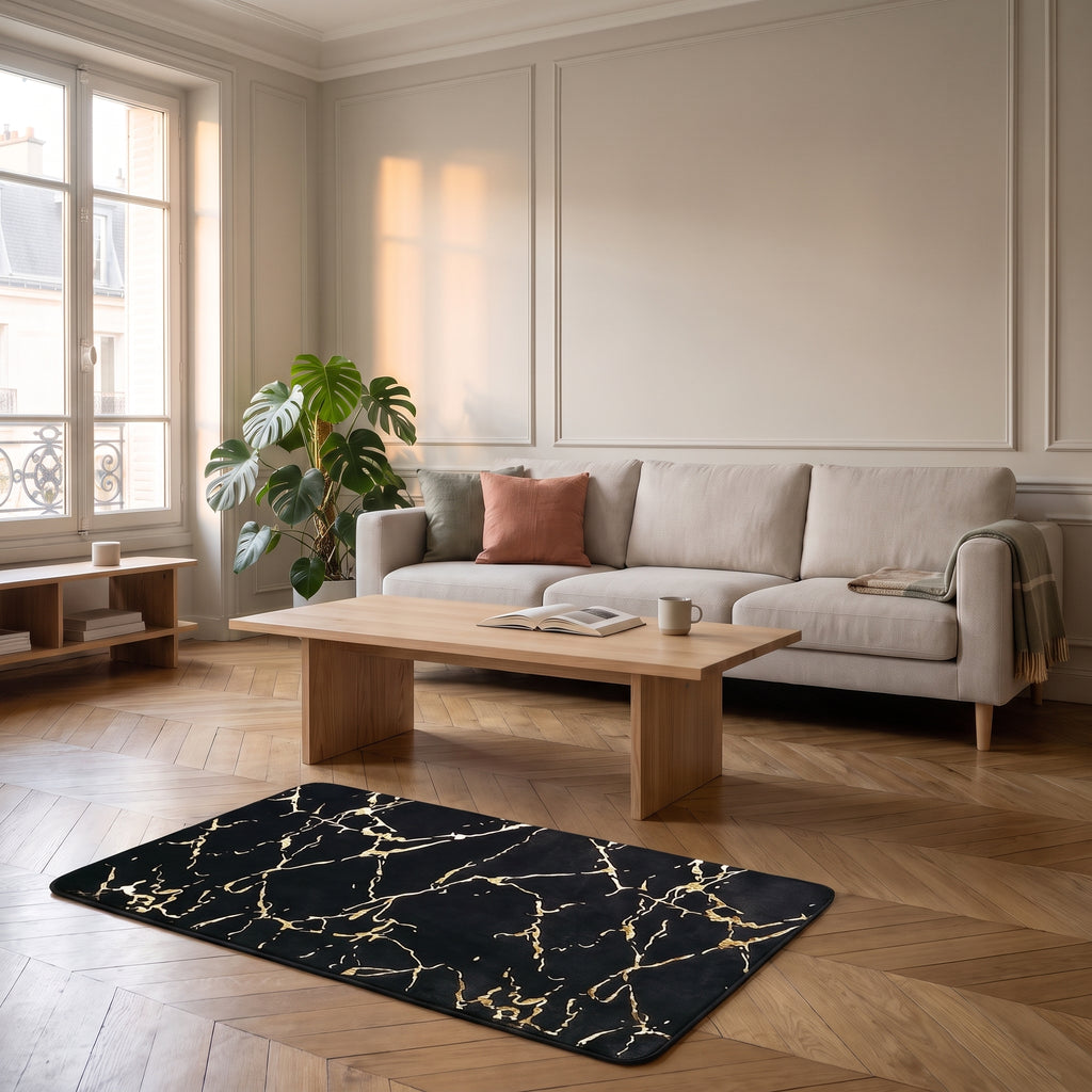 Tapis effet marbre noir veiné d'or posé à plat sur le parquet en chevrons du salon, devant le canapé en tissu clair