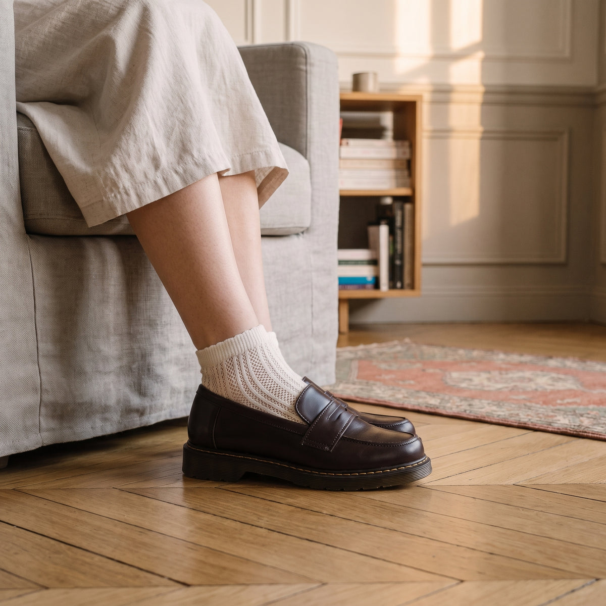 Socquette écrue en maille ajourée dépassant d'un mocassin brun, sur un parquet en point de Hongrie Image