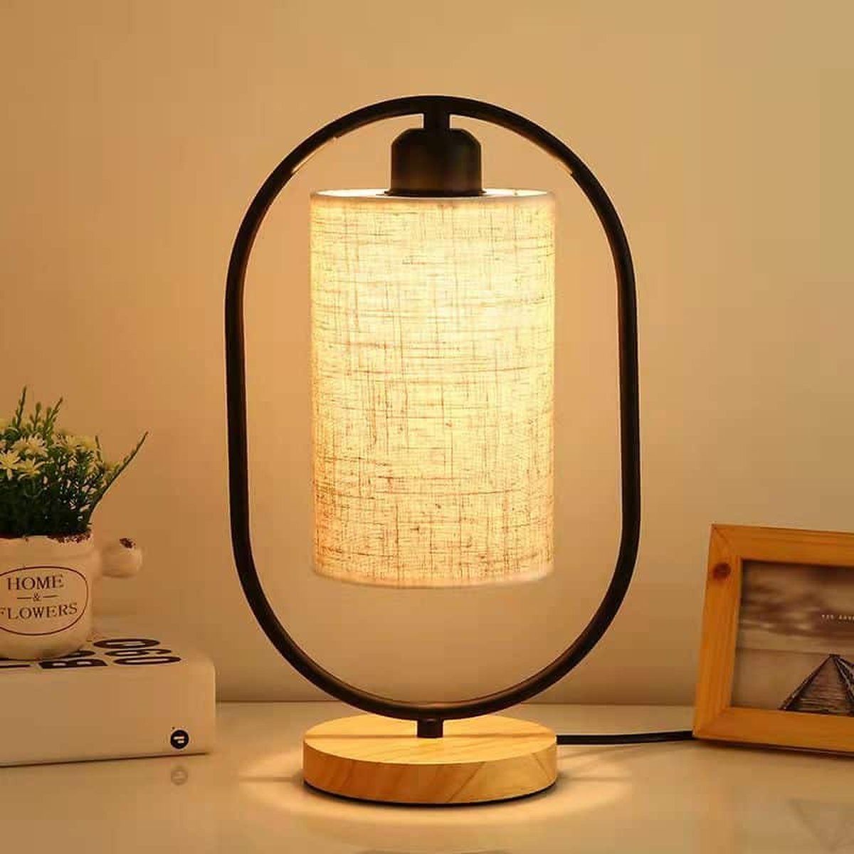 Lampe de chevet noire à structure ovale, socle en bois et abat-jour en lin allumé