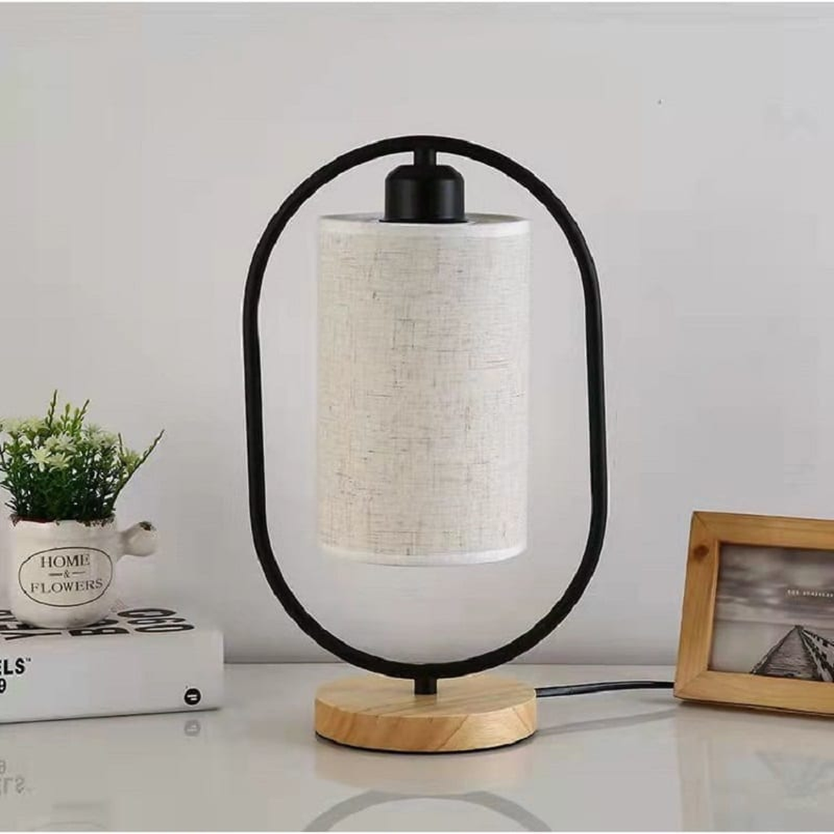 Lampe de chevet noire éteinte avec structure ovale, socle en bois et abat-jour en lin