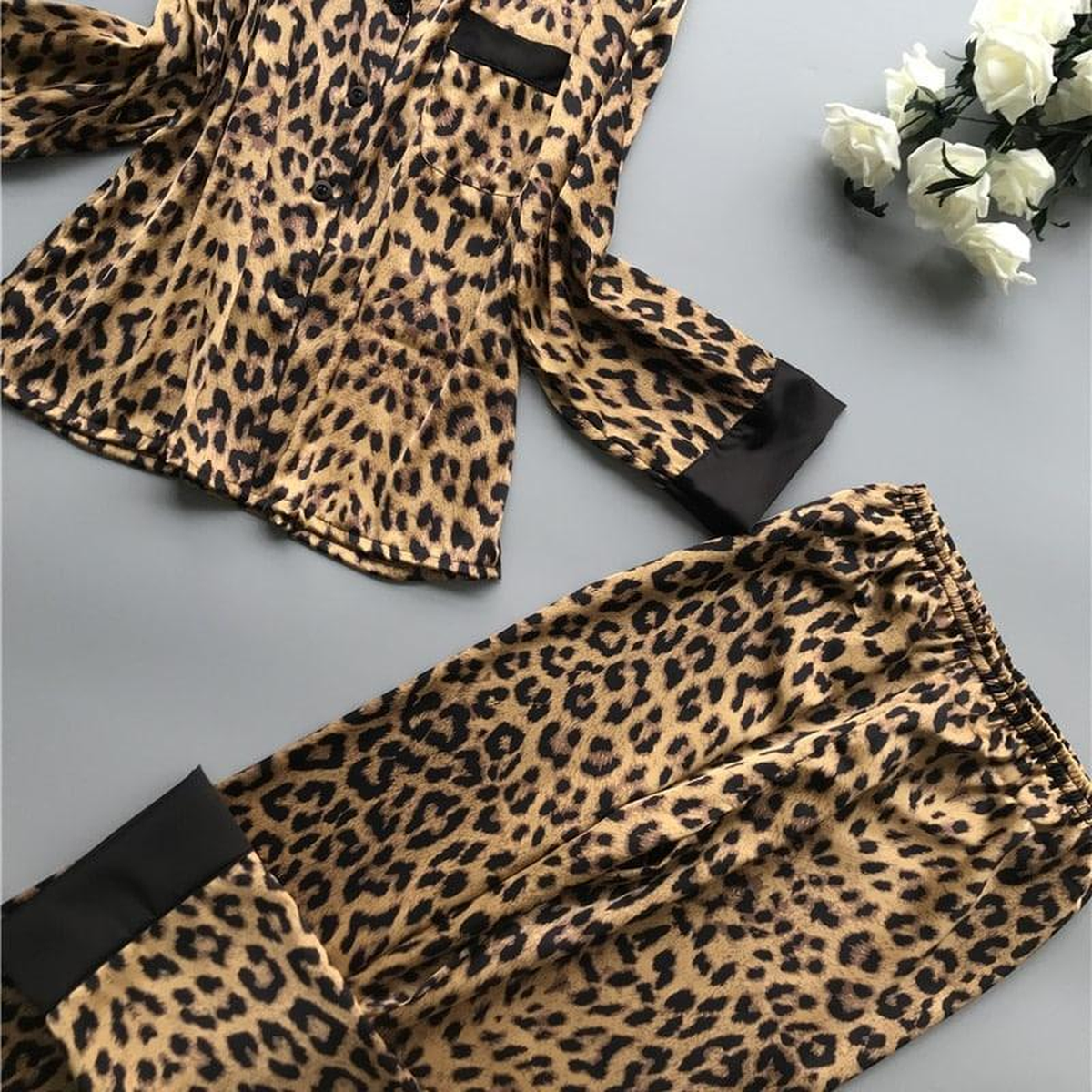 Détail du pantalon de pyjama en satin imprimé léopard, parement noir au bas