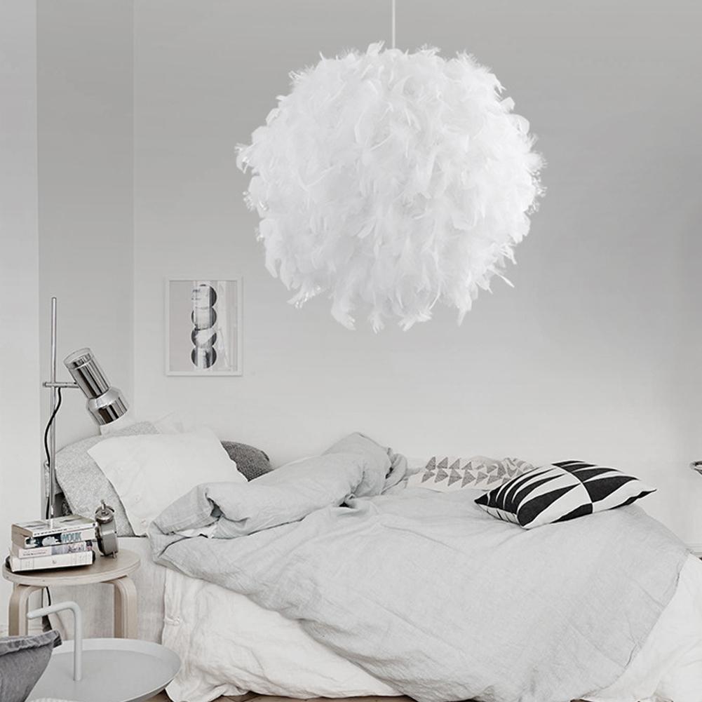 Suspension boule à plumes blanche allumée au-dessus d'un lit, produit au premier plan