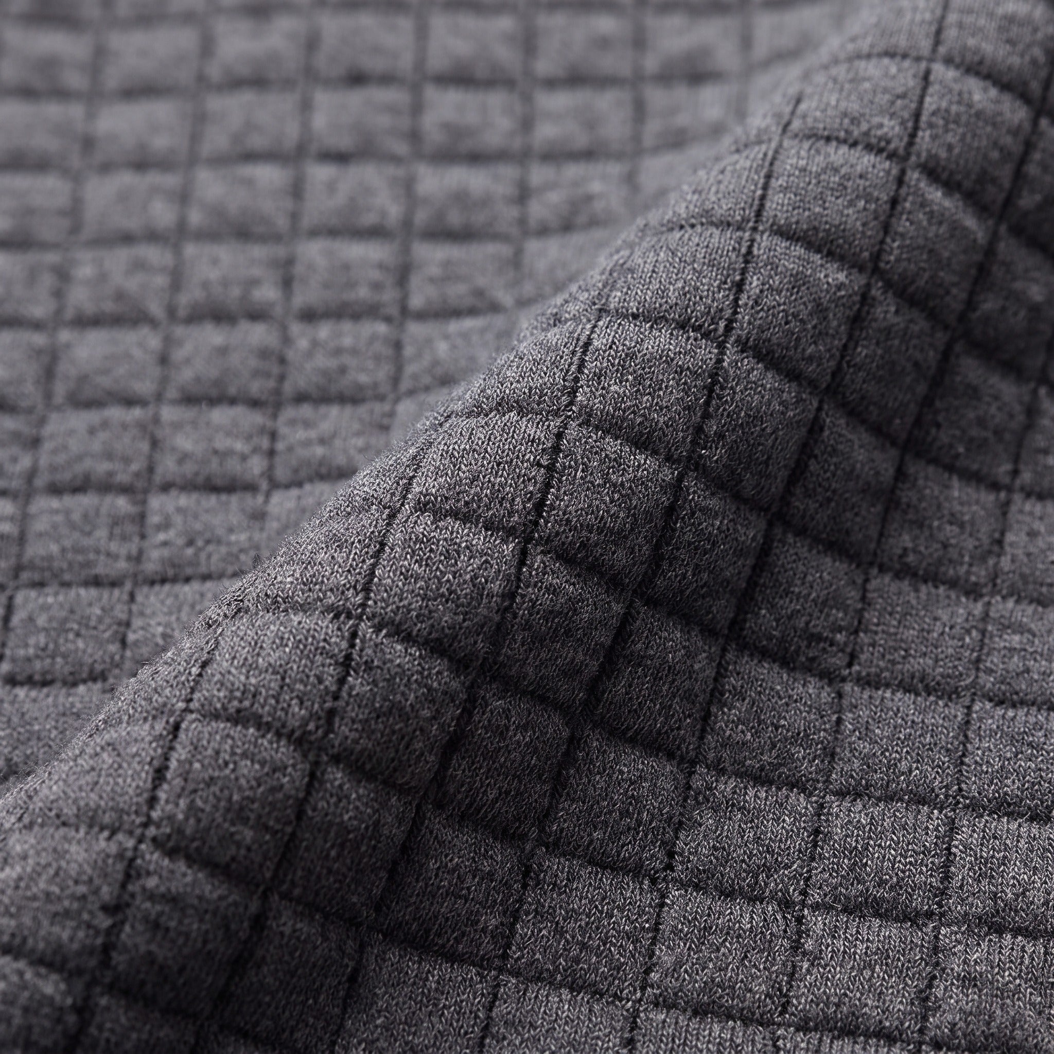 Gros plan sur la maille gaufrée du sweat : un damier de petits carrés bombés séparés par des sillons creusés. Image