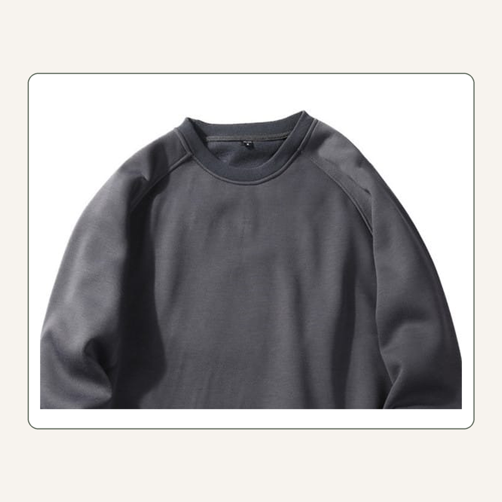 Détail du col rond et des coutures raglan du sweat homme gris foncé