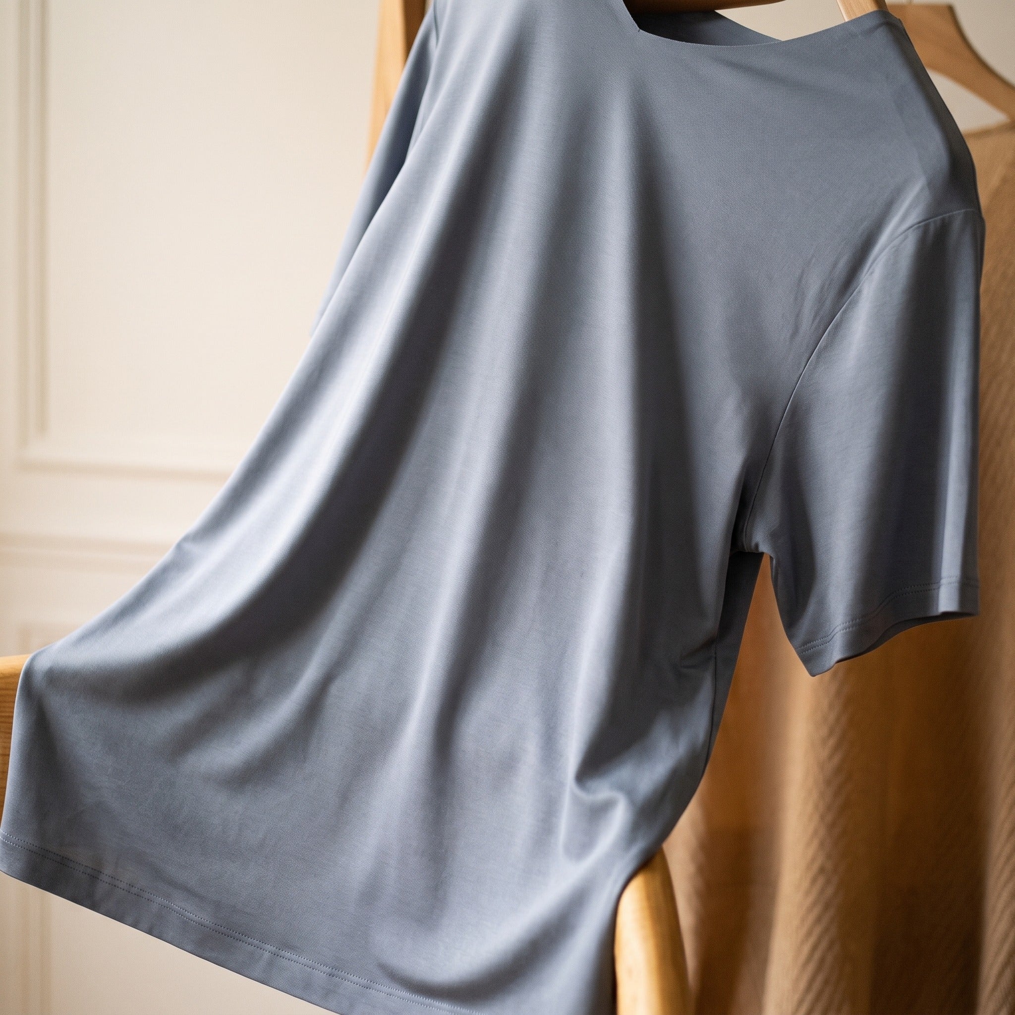 Cote d un t-shirt col V gris suspendu a un cintre : le tissu descend du dessous de bras jusqu a l ourlet en une seule surface Image