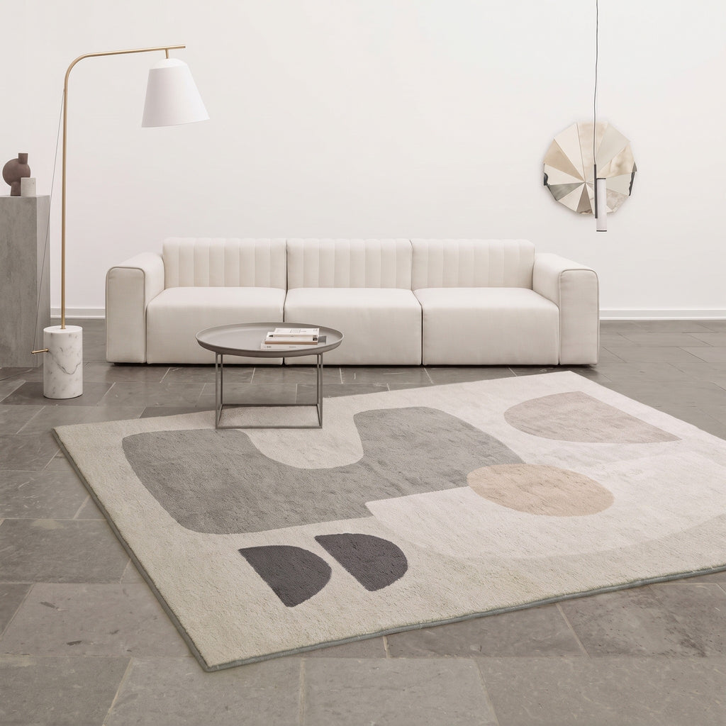 Tapis abstrait a formes geometriques grises pose dans un salon clair, photo du fabricant