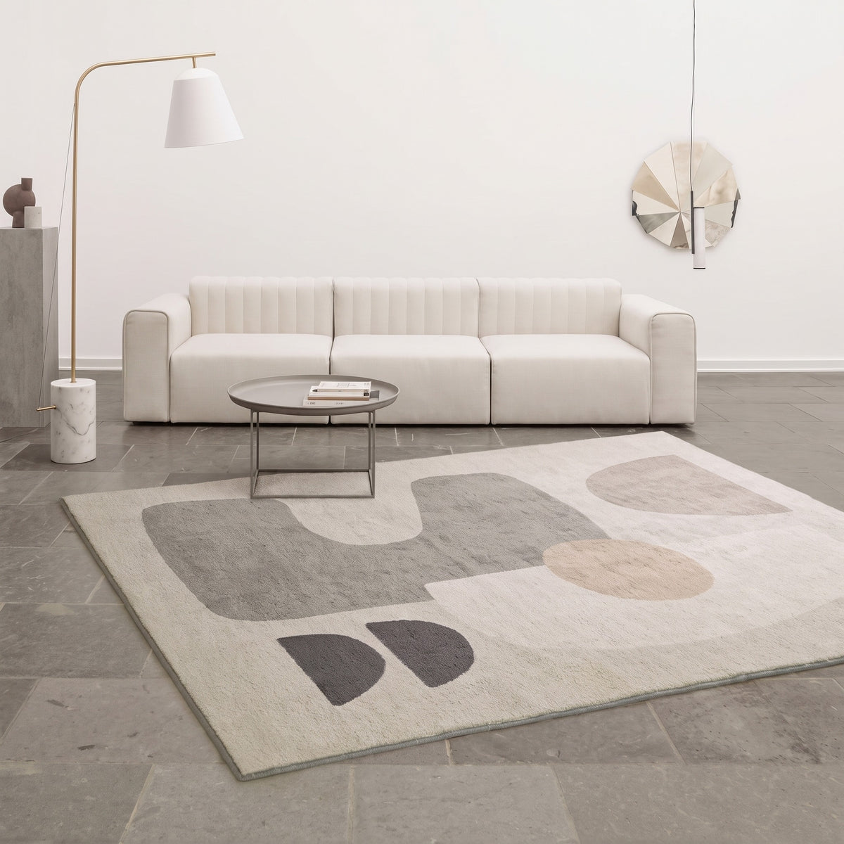 Tapis abstrait a formes geometriques grises pose dans un salon clair, photo du fabricant