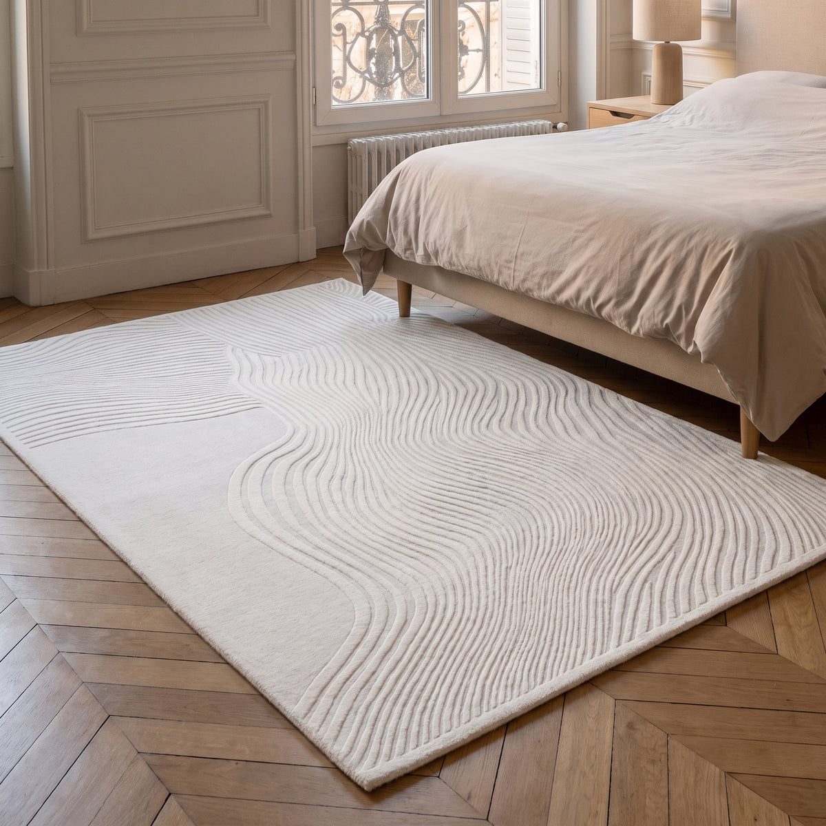 Tapis blanc craie à vagues sculptées posé au pied d'un lit
