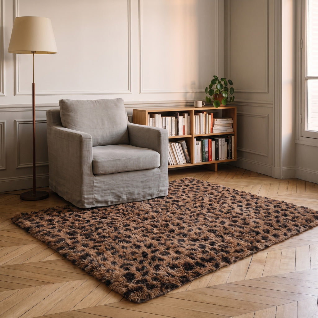 Tapis leopard chocolat pose dans un coin lecture, devant un fauteuil en lin gris