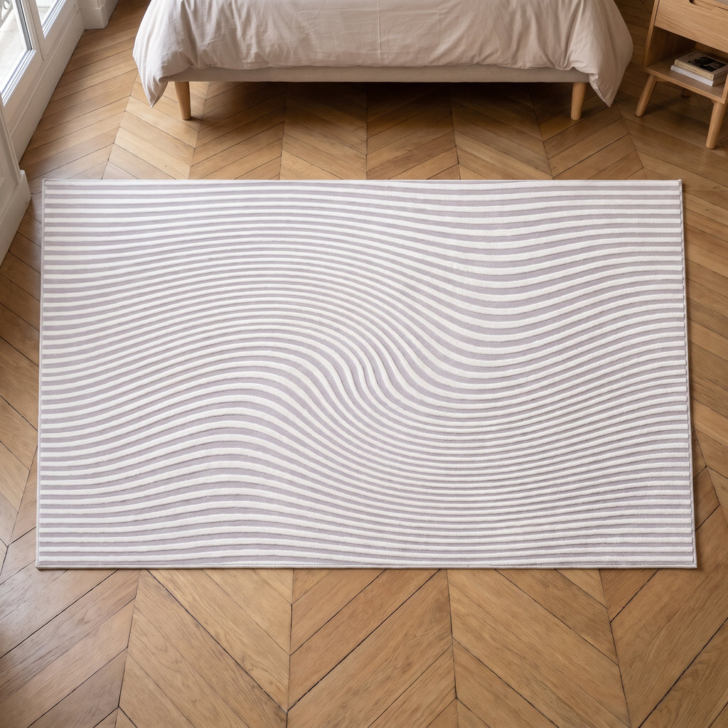 Tapis à ondes sculptées en relief, coloris gris lilas, tapis entier vu d'aplomb dans une chambre claire