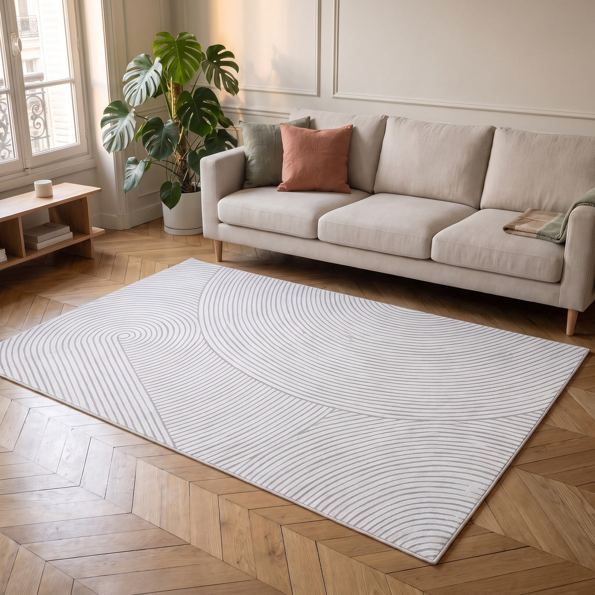 Tapis à ondes sculptées en relief gris perle, motif spirale, posé devant le canapé d'un salon clair