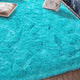 Tapis à poils longs coloris bleu turquoise, déployé au sol d'une pièce