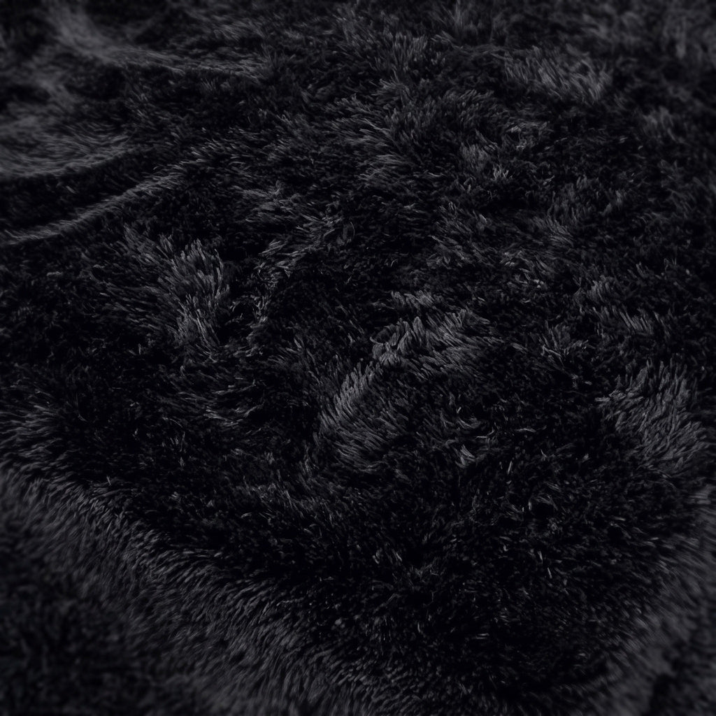 Surface d'un tapis noir à poils longs vue de très près, fibre nette en lumière du jour