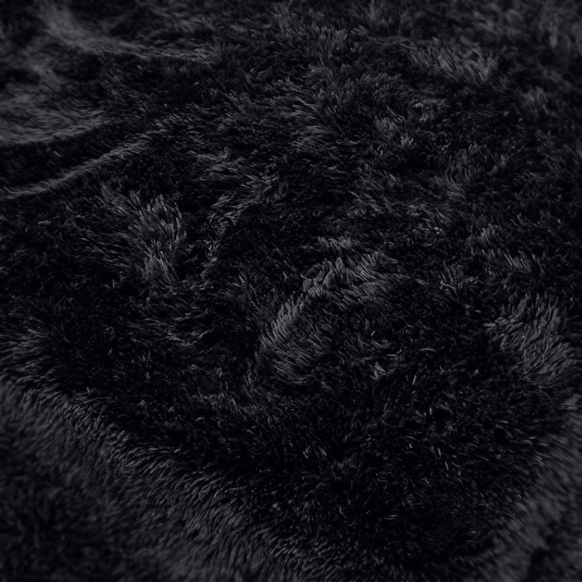 Surface d'un tapis noir à poils longs vue de très près, fibre nette en lumière du jour