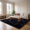 Tapis noir à poils longs posé au sol d'un salon haussmannien clair, devant un canapé en lin et une table basse en bois