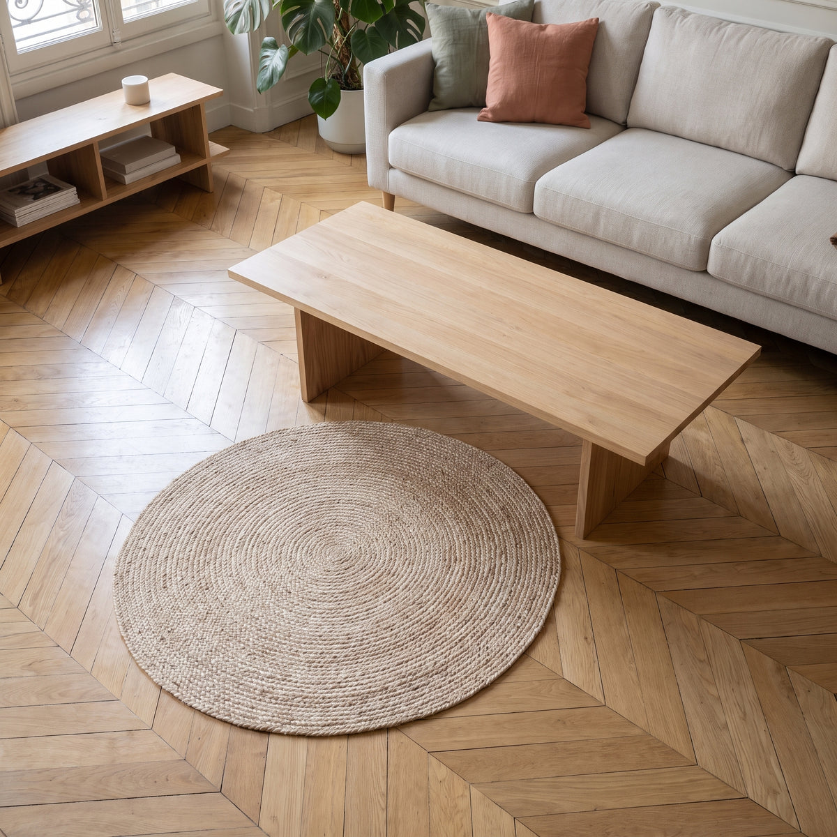 Tapis rond en sisal beige posé sur le parquet d'un salon, devant une table basse en bois clair Image