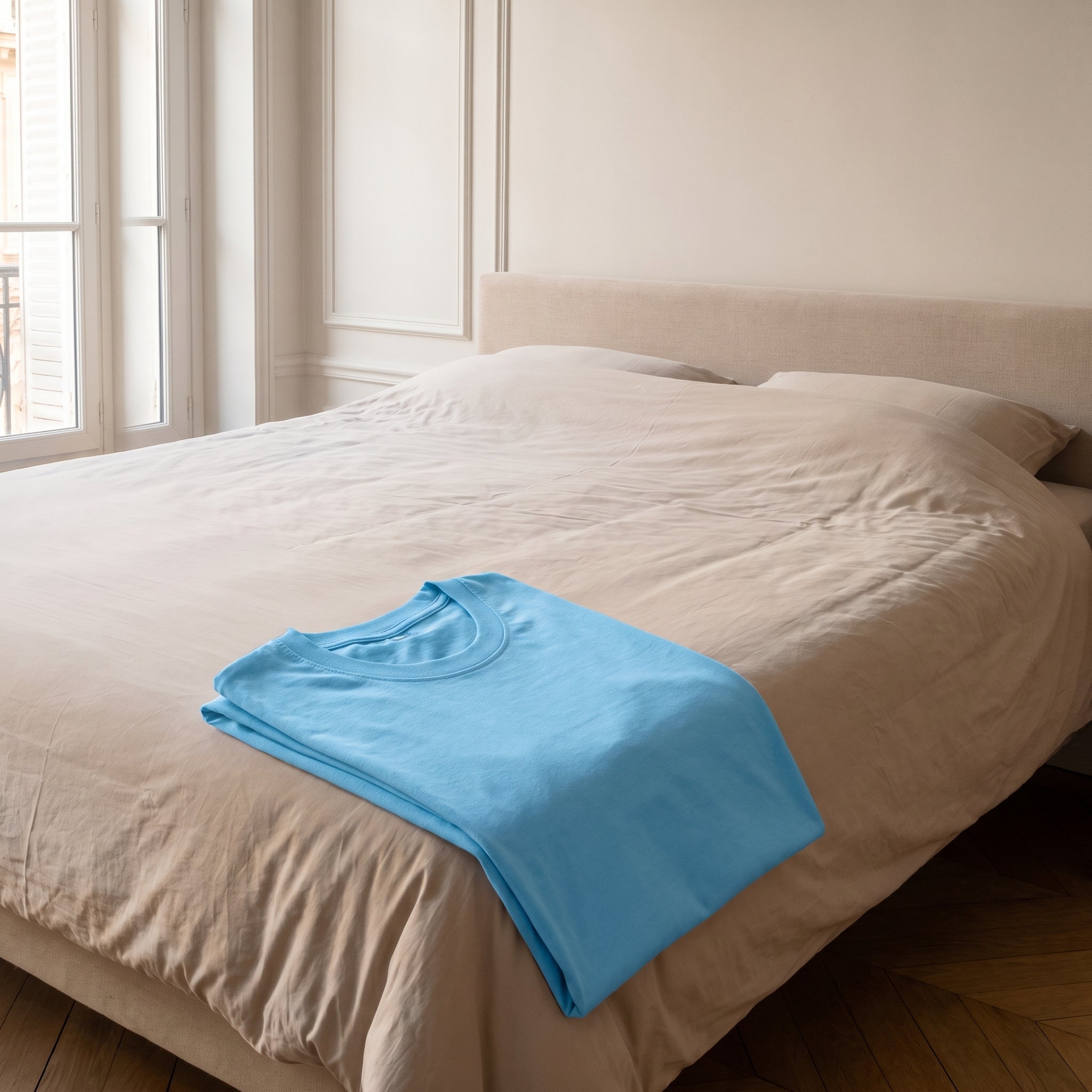 T-shirt cocooning bleu clair plié sur un lit fait, prêt pour la nuit Image