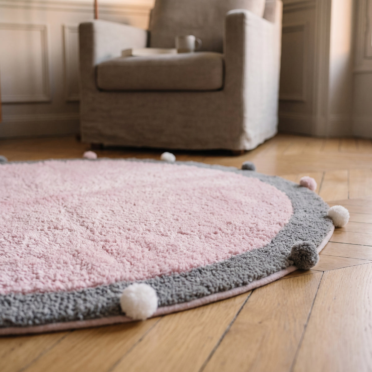 Gros plan sur le duvet moelleux et la bordure à pompons du tapis rond rose Image