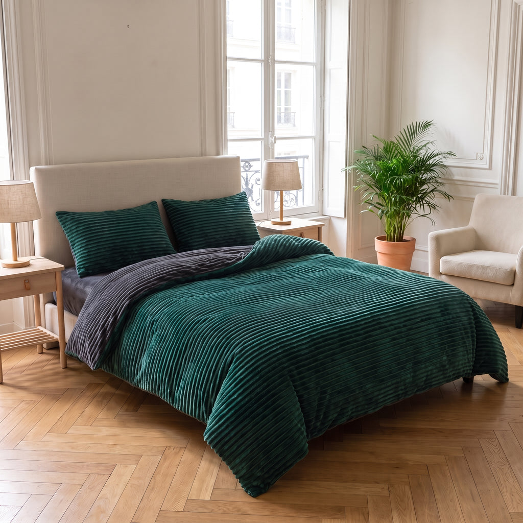 Lit double avec la parure verte côtelée dans une chambre haussmannienne lumineuse