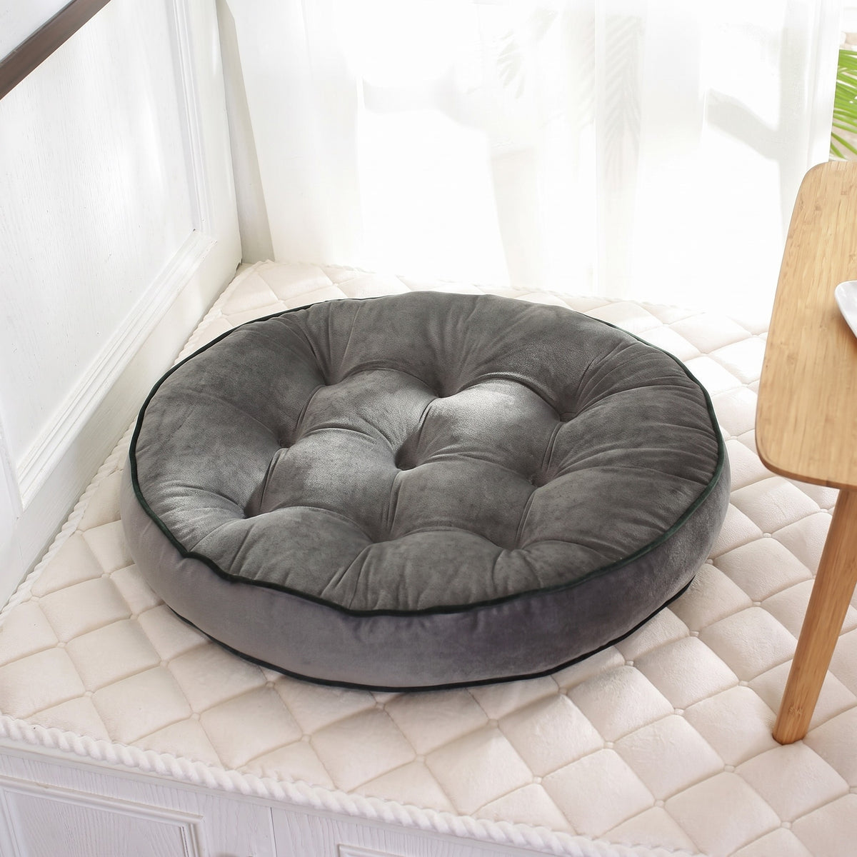 Coussin de sol rond façon tatami coloris gris, posé au sol dans un coin lumineux