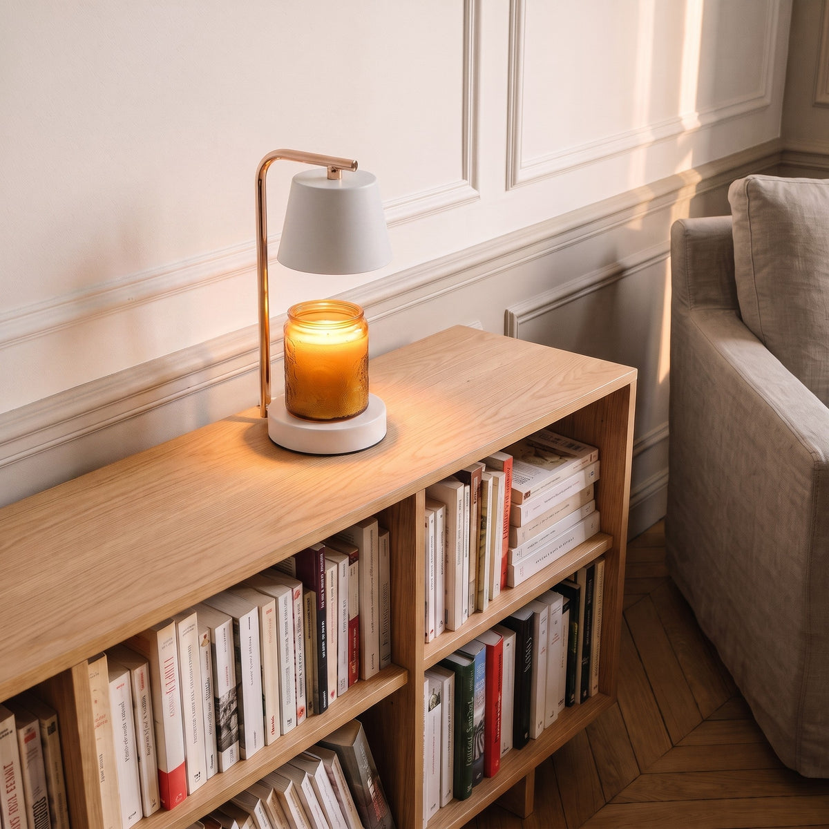 Lampe chauffe-bougie blanche allumée sur le plateau d'une bibliothèque basse, dans un coin lecture