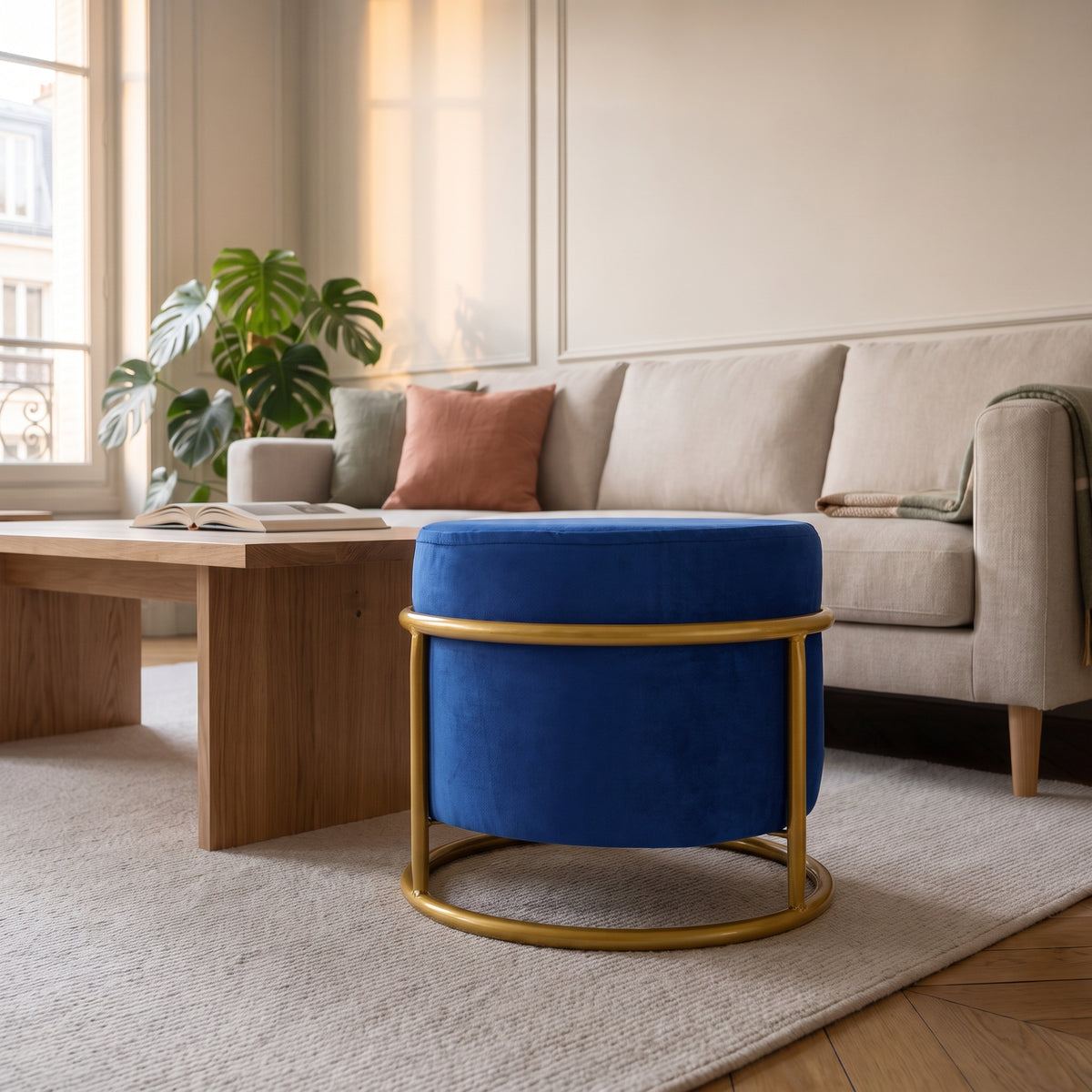 Pouf réglable bleu roi sur sa structure dorée, devant le canapé du salon